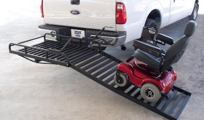 Folding Mighty Lite Aluminum Scooter and Power Chair Carrier on a vehicle's hitch receiver, featuring a folded ramp and tie-down eyelets, designed for easy loading and secure transportation.