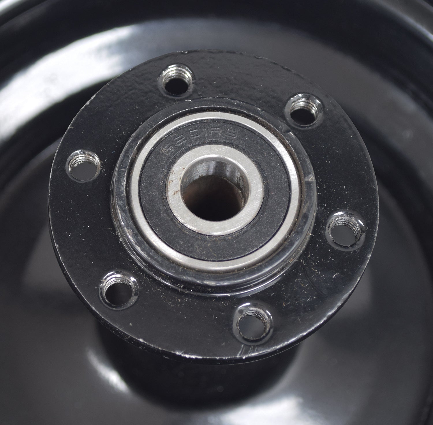 Rear Wheel Rim for the Monster Moto / Mega Moto Classic 80cc, 105cc, & 1000w mini bike models, featuring a black metal design with multiple holes and pre-installed bearings and spacer.