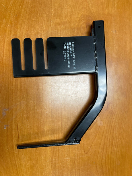 Leg Rest Hanger Receiver for the Universal Seat Frame on Jazzy Power Chairs (Missing Hardware) displayed on a wooden surface, showing the black rectangular metal object with white text and tool-like features.