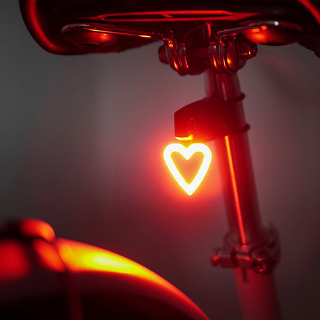 HeartThrob USB Tail Light for Bikes & Scooters: a heart-shaped LED light mounted on a bicycle seat, designed for rear safety with five illumination modes and a rechargeable battery.