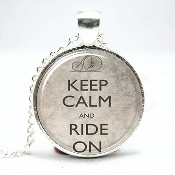 Keep Calm and Ride On Pendant & Chain featuring a silver plate finish, domed glass, and a 16 chain with a 1 diameter pendant, perfect for cyclists and steampunk enthusiasts.