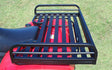 Mighty Lite ATV Rear Aluminum Rack mounted on a red lawnmower, showcasing its sturdy black metal construction and functional design for enhanced storage on various ATV brands.