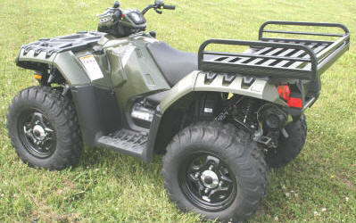 Mighty Lite ATV Rear Aluminum Rack mounted on an ATV, parked on grass. Close-up shows sturdy metal construction and ample storage space, highlighting its durable and rust-resistant build.