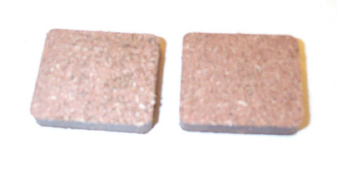 Close-up of Organic Brake Pads for Arctic Cat Snowmobiles (1981-2000), showcasing a pair of cork coasters-like brake pads known for their lightweight, dependable performance in extreme temperatures.