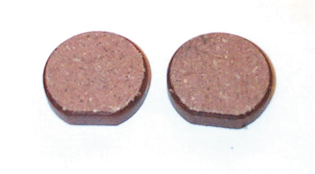 Close-up of two round Organic Brake Pads for Polaris Snowmobiles (1975-1981), showcasing their texture and form, highlighting their dependable performance in extreme conditions.