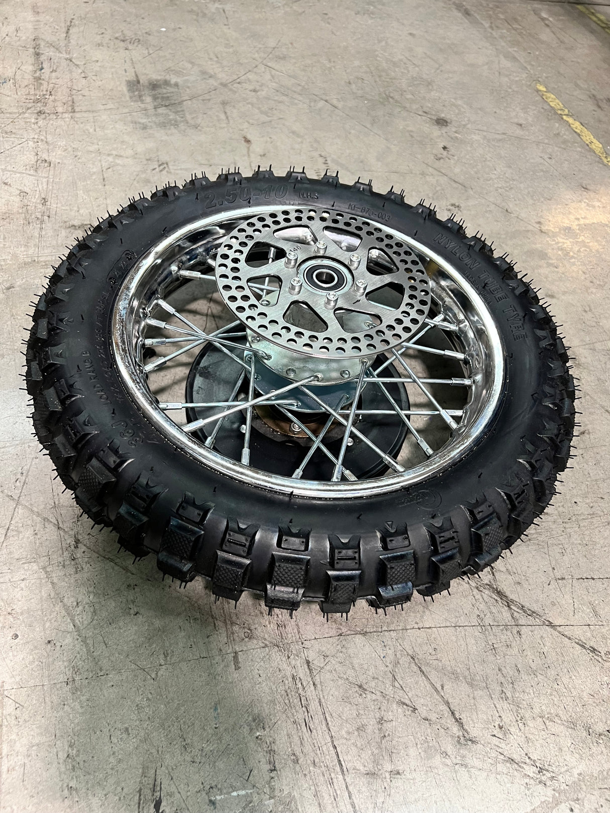 Rear Wheel Assembly for Razor MX500 and MX650, showing a spoked rim, tire, and brake rotor, designed for the Dirt Rocket models, including the axle, sprocket, and inner tube.