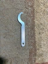 13-1/2 Adjustable Air Shocks for ATVs, Dirt Bikes & Go-Karts (Set of 2) on a concrete surface, showcasing a silver wrench nearby.