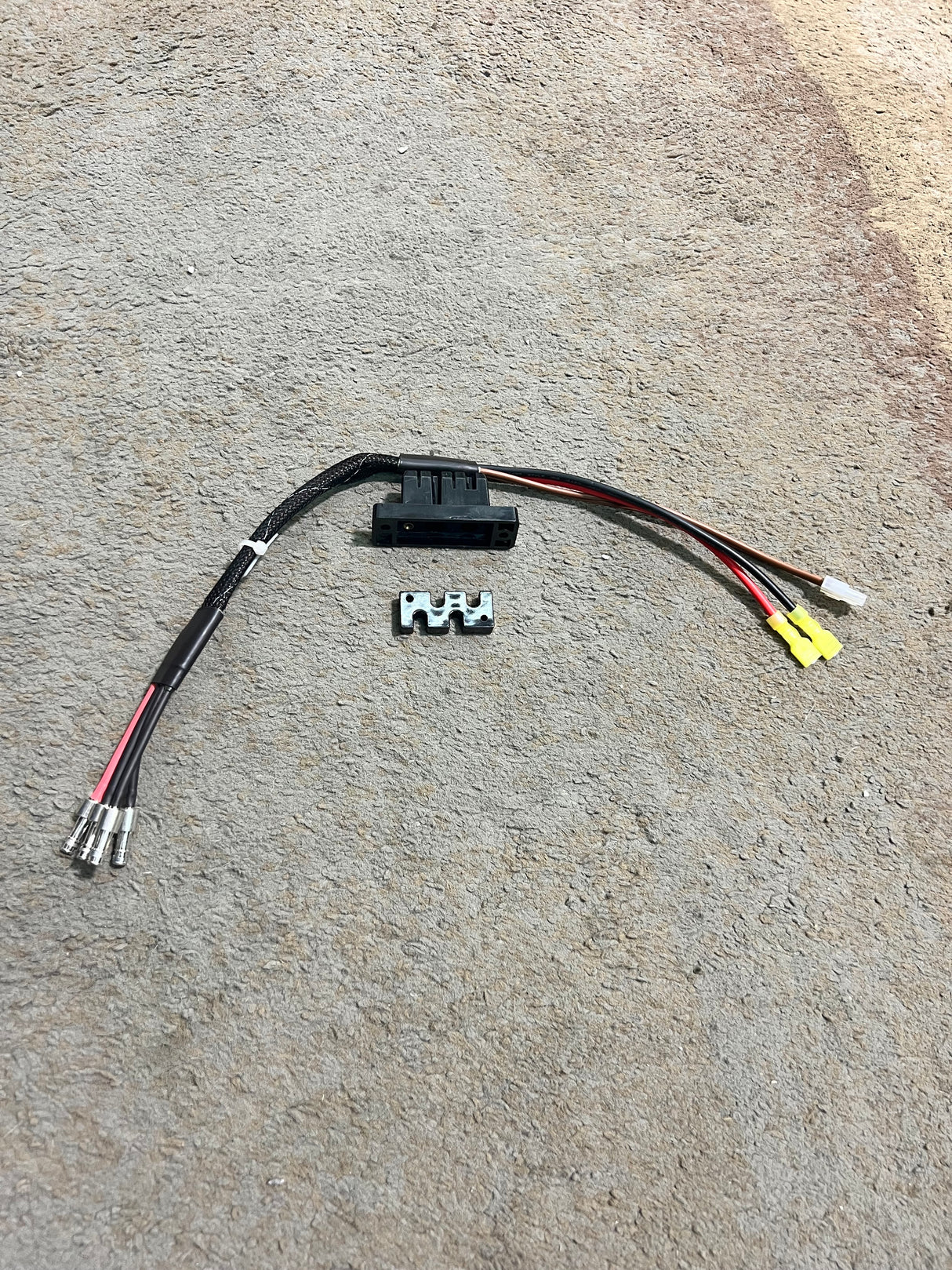 Motor, Brake, & Controller Harness for the Go-Go Elite Traveller, Elite Traveller Plus, Sport, & Ultra X Scooters, displaying black and red electrical wires with a black plastic connector on a concrete surface.