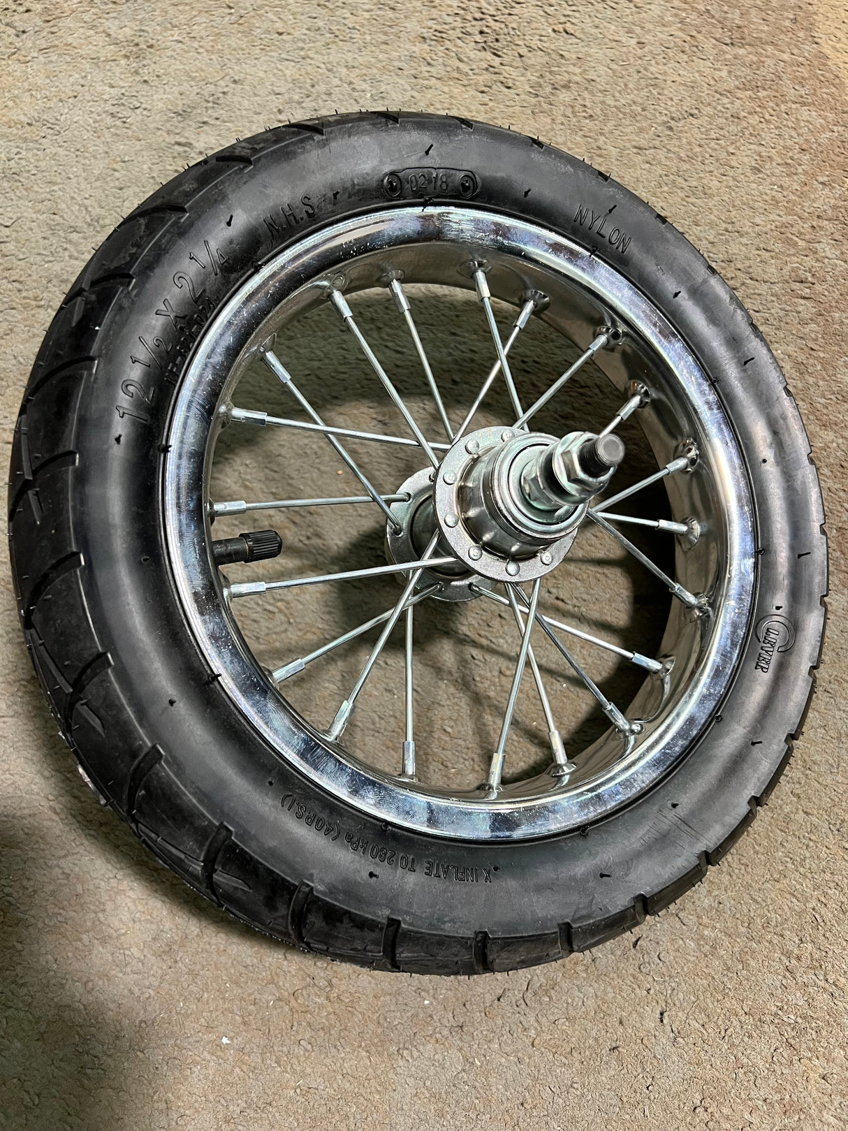 Rear Wheel Assembly with Wire Spoke Rim for the Razor Pocket Mod (Versions 31+), featuring a 12-1/2 x 2-1/4 tire, visible spokes, rim, and band brake, placed on the ground.