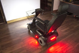 Light Kit for Mobility Scooters and Power Chairs featuring a black scooter with red lights, a wire basket on the front, and close-up views of the lights and tires.