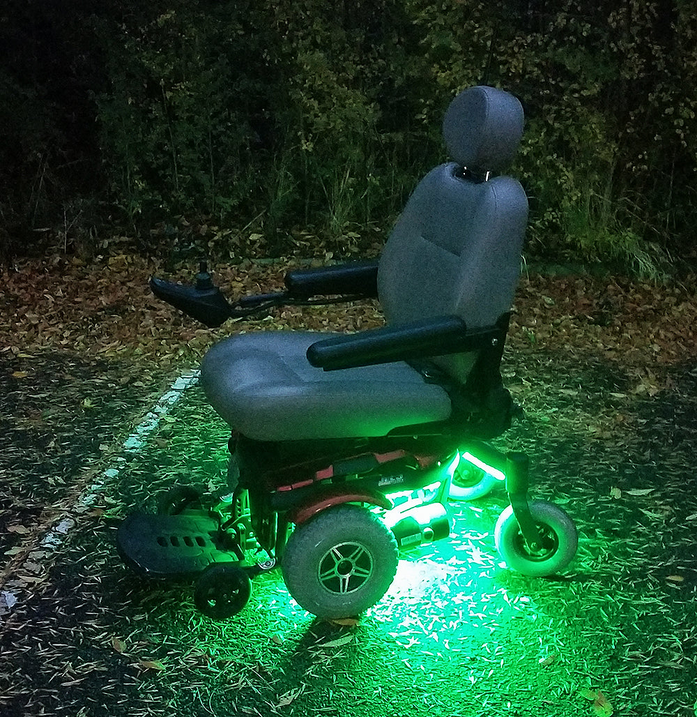 Multi-Color LED Light Kit for Jazzy Power Chairs: A wheelchair equipped with glowing LED lights, positioned outdoors on grass. The lights can pulse, flash, or cycle, enhancing visibility and style.