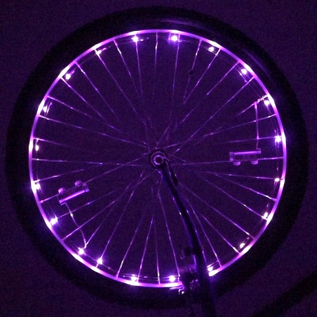 LED Bicycle Rim Spoke String Lights illuminating a bicycle wheel with vibrant purple LEDs, enhancing visibility. The lights are wrapped around the spokes, showcasing their steady and flash modes for added safety.