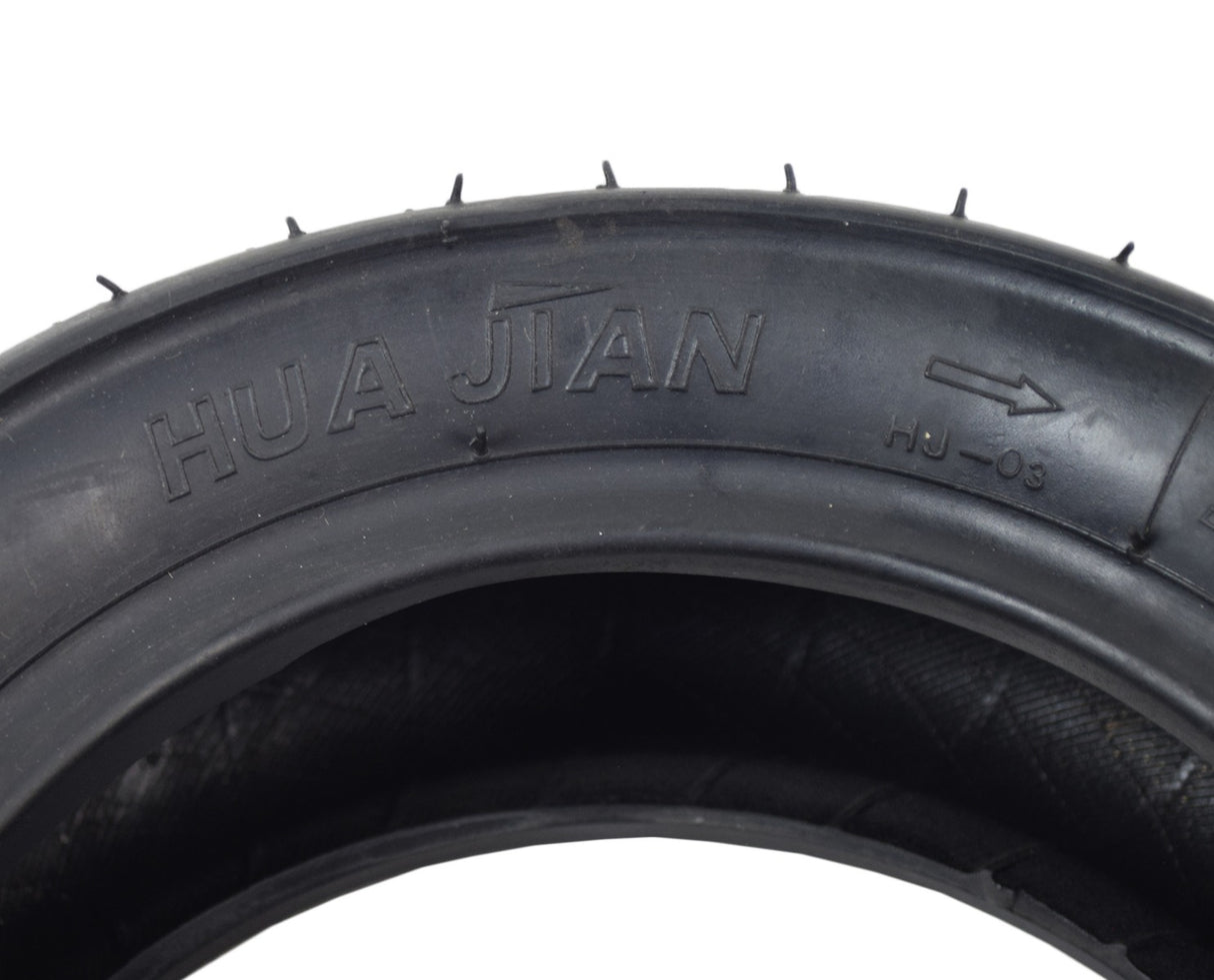 110/50-6.5 Tire for the Motovox MBxXSe Micro-Mini Bike, featuring close-up of shallow grooved tread for excellent traction, with visible text and logo carvings on the black synthetic rubber surface.