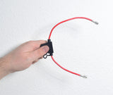 Hand holding an In-line 30 Amp ATM Blade Fuse Holder with Wire & 1/4 Battery Terminal Connectors, showcasing the red and black cables attached to the fuse holder.