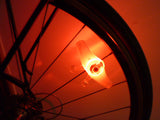 Rechargeable Bicycle Spoke Light attached to a bicycle wheel, illuminated and visible within the spokes, enhancing visibility and safety for cycling in low-light conditions.