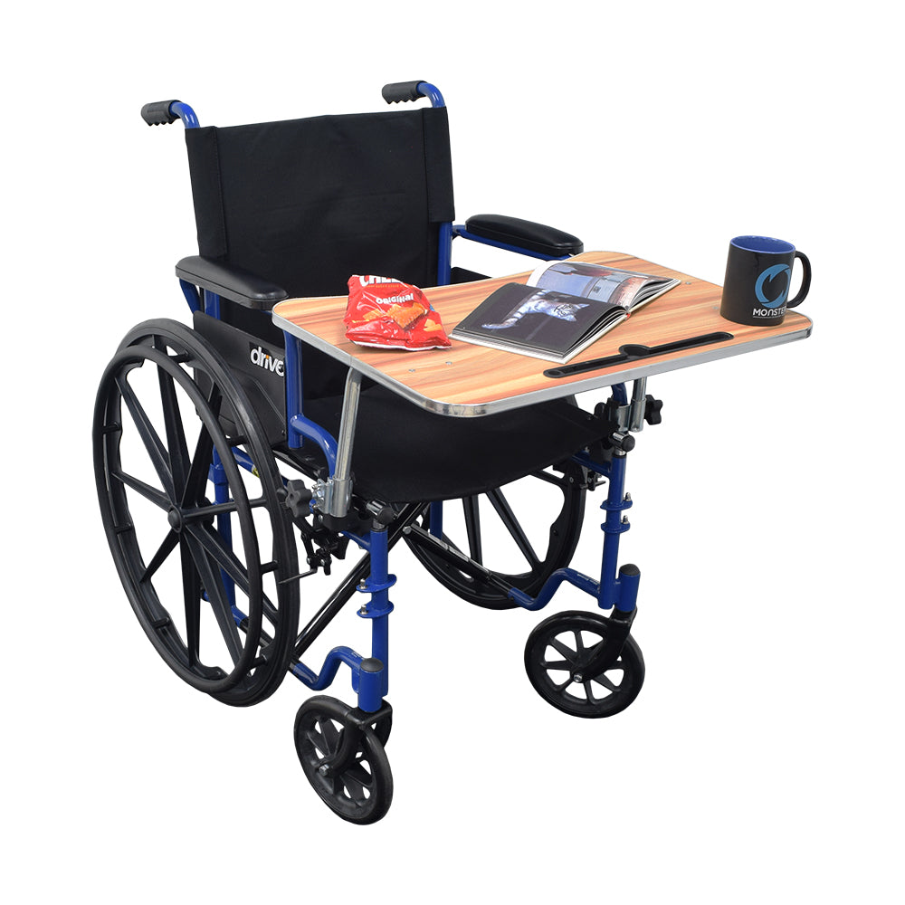 Wood Veneer Tray Table for Wheelchairs (Blemished) attached to a wheelchair, featuring an open book, a black mug with a blue design, and a snack bag on the table.