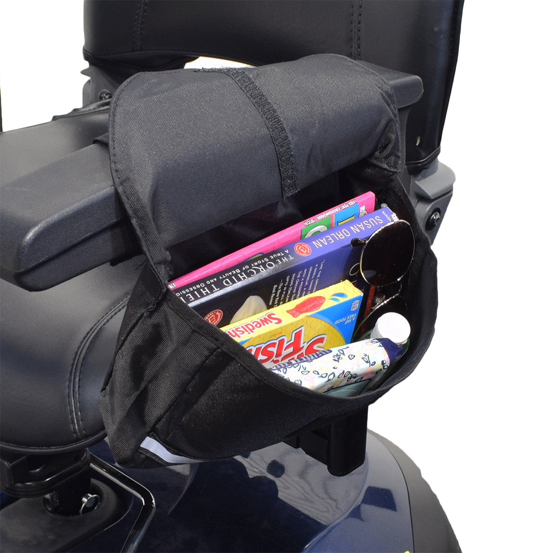 Saddle Bag for Mobility Scooters, Power Chairs, & Wheelchairs with books, sunglasses, and a cartoon-faced white object, featuring secure Velcro and zipper pouches.