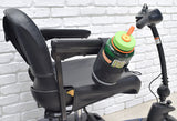 Unbreakable Universal Cup Holder for Mobility Scooters, Power Chairs, & Wheelchairs shown mounted on a chair, holding a green bottle with an orange cap. Durable, versatile, and easy to attach.