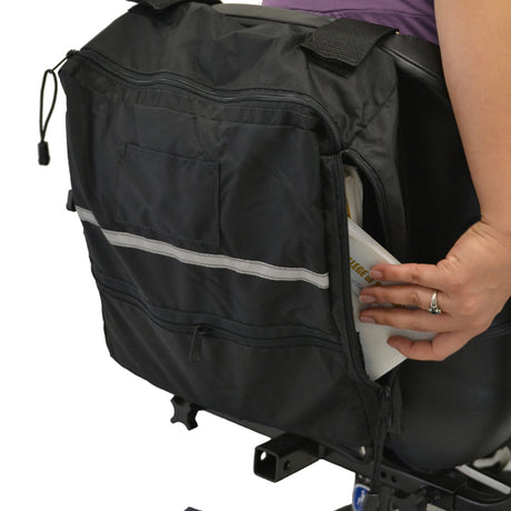 Side Access Seatback Bag for Mobility Scooters, Power Chairs, & Wheelchairs, shown being attached to the back of a bike, with visible zippers and a person holding it.