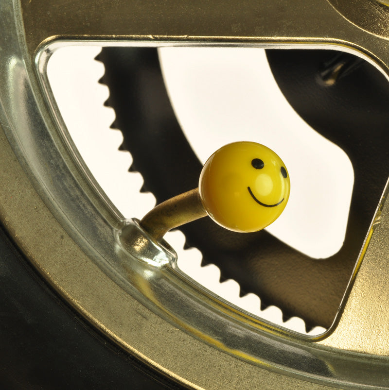 Mister Smiley ABS Valve Stem Cap Cover featuring a yellow smiley face on a gear wheel, designed to replace standard valve caps on bikes, scooters, and motorcycles.