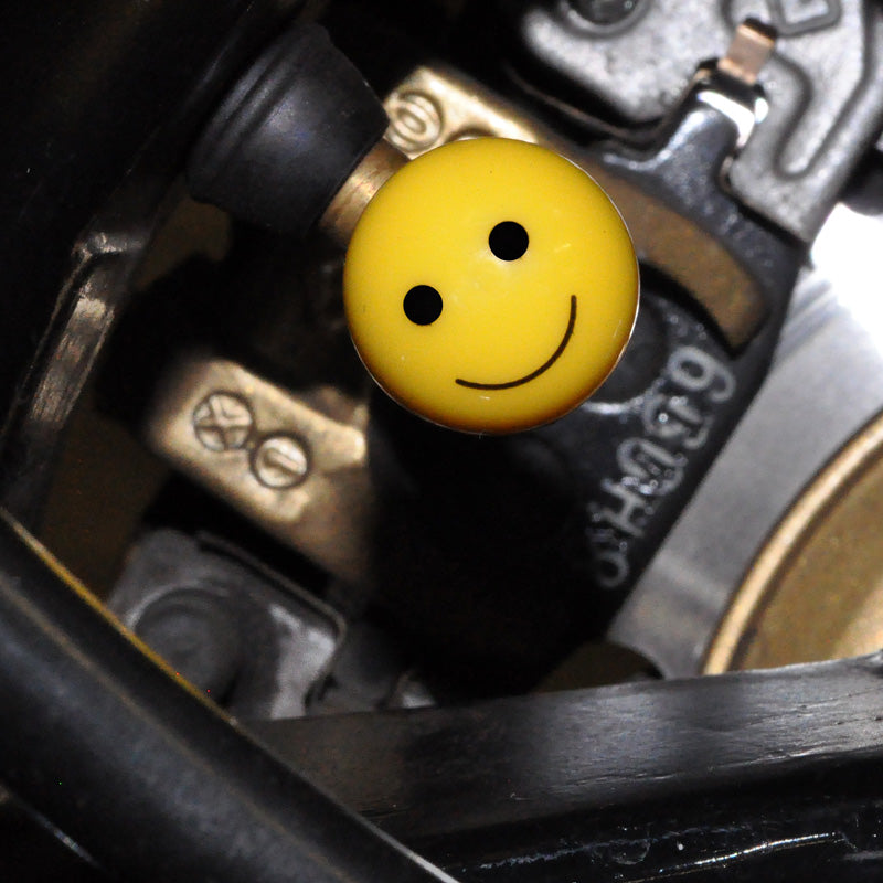 Mister Smiley ABS Valve Stem Cap Cover, a 3/4 yellow ball with a cheerful smiley face, designed to replace standard black plastic caps on bike and scooter Schrader valves.