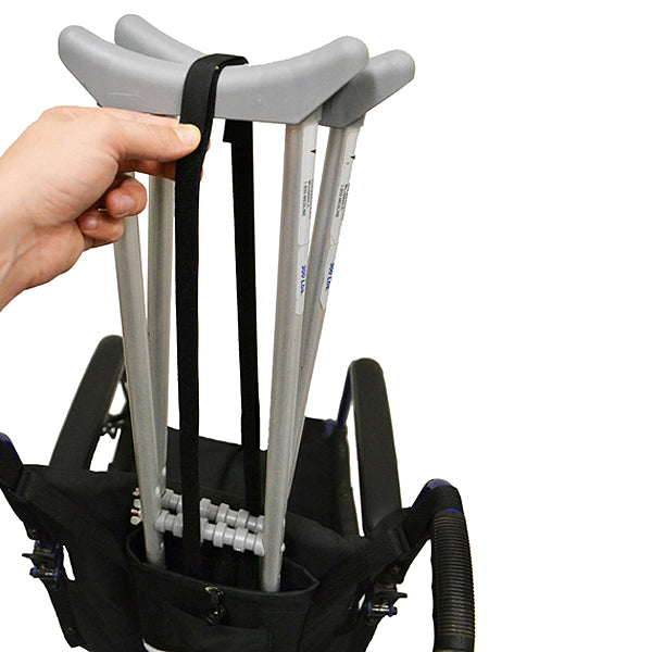 Hand holding the Universal Crutch Holder for Wheelchairs, a durable polyester strap designed to secure crutches behind manual wheelchair push-handles, fitting both forearm and underarm crutches securely.