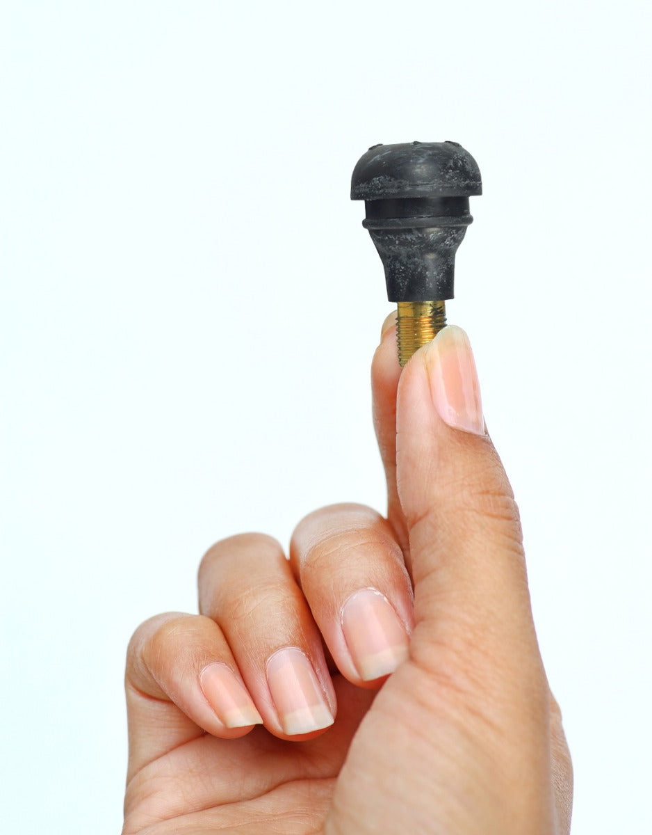 Person's hand holding a Straight Valve Stem for Tubeless ATV, Dirt Bike, & Scooter Tires, showing close-up details of the black and gold stem with a universal 15mm mount diameter.