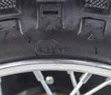 Close-up of the Rear Wheel Assembly for Razor MX500 and MX650, highlighting the tire tread, axle, rim, sprocket, and brake rotor. A screw is visible embedded in the tire.