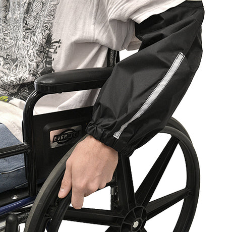 A person in a wheelchair using Sleeve Guards for Wheelchair Users, which cover their forearms, protecting clothes from mud and water splashed up from the wheels.