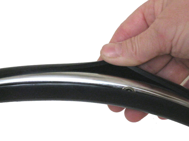 Hand holding a black and silver vinyl cover, part of a Set of Two Vinyl Covers for Wheelchair Hand Rims, designed to improve grip and convenience for wheelchair users.