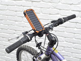 Portable Dual USB Battery Power Bank/Charger & Universal Grip Holder mounted on a bicycle with an attached solar panel, including close-ups of the bike tire and handlebar.