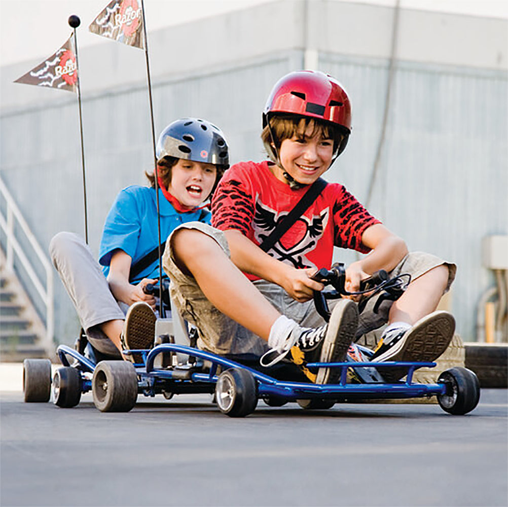 Two young boys wearing helmets ride a small blue go-kart, the Razor Ground Force Drifter, powered by a 24 Volt Battery Pack for enhanced playtime.