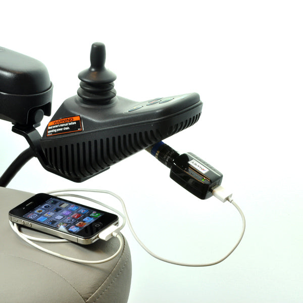 USB Charging Adapter for Scooters and Power Chairs: A phone with a white cable is charging on a seat using the adapter, highlighting its functionality for electronic devices via an XLR to USB connection.